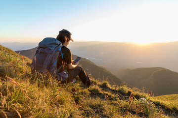 Fototapeta premium Traveler woman relaxing meditation with serene view mountains. Girl enjoying a view from the top of mountain. Relaxing alone with nature.