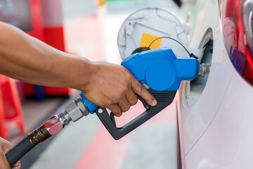 Hand holding gas nozzle with one last drop. A man holding a gasoline nozzle.