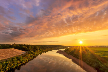 amazing view at beautiful summer river sunset, halo with reflection on water with green bushes,...