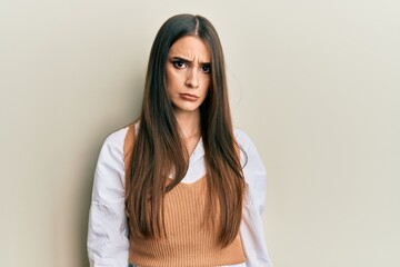 Beautiful brunette young woman wearing casual clothes skeptic and nervous, frowning upset because...