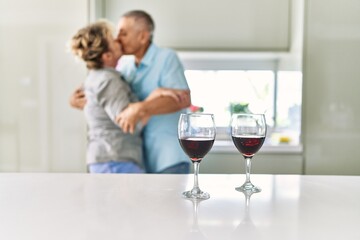 Senior caucasian couple kissing and dancing at the kitchen.