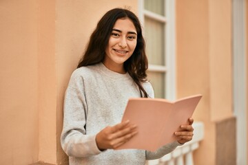 Naklejka premium Young middle east student girl smiling happy reading book at the city.