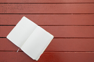 The notebook is placed on a wooden table in the garden, top view.