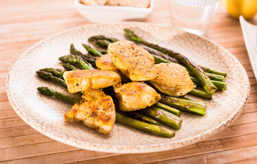 cooked dish. Chicken nuggets with green asparagus on plate