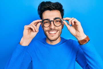 Young hispanic man wearing glasses smiling with a happy and cool smile on face. showing teeth.