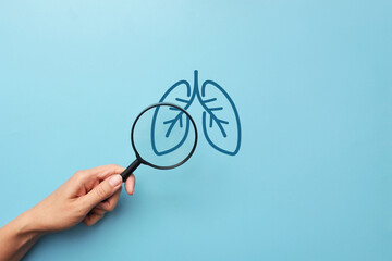 A person examines the lungs through a magnifying glass. A symbol for the diagnosis of lung diseases