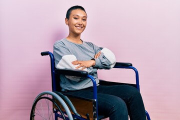 Beautiful hispanic woman with short hair sitting on wheelchair happy face smiling with crossed arms...