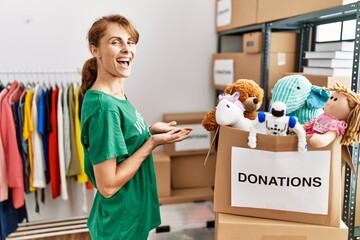 Beautiful caucasian woman wearing volunteer t shirt at donations stand pointing aside with hands...