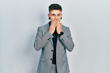 Young caucasian boy with ears dilation wearing business jacket laughing and embarrassed giggle...