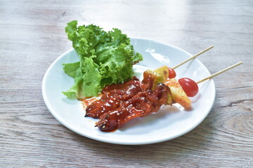roasted beef meat with pineapple chili and tomato dressing barbecue sauce stabbing wooden stick on plate