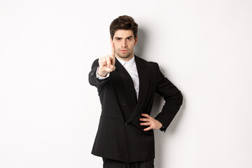 Portrait of serious handsome man in business suit, showing one finger to prohibit or decline...