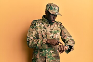 Young african american man wearing army uniform in hurry pointing to watch time, impatience, upset and angry for deadline delay
