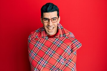 Handsome hispanic man wrapped in a red warm red blanket smiling and laughing hard out loud because funny crazy joke.