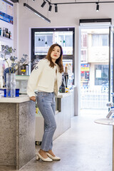 Pretty young asian woman wearing casual clothing and posing in modern cafe. 