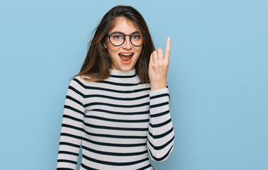 Young beautiful teen girl wearing casual clothes and glasses pointing finger up with successful idea. exited and happy. number one.