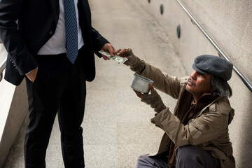 Old homeless man grab money from businessman