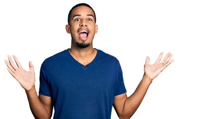 Young african american man wearing casual t shirt celebrating crazy and amazed for success with arms raised and open eyes screaming excited. winner concept