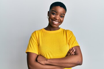 Young african american woman wearing casual yellow t shirt happy face smiling with crossed arms...