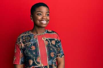 Young african american woman wearing african style looking away to side with smile on face, natural expression. laughing confident.