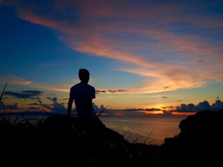 silhouette of a person at the sunset cliff and the ocean