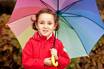 Little child with multicolored rainbow umbrella outdoors