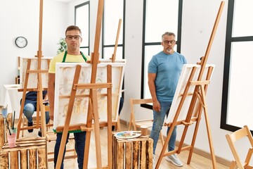 Group of middle age people artist at art studio thinking attitude and sober expression looking self confident