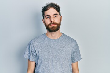 Obraz premium Caucasian man with beard wearing casual grey t shirt relaxed with serious expression on face. simple and natural looking at the camera.
