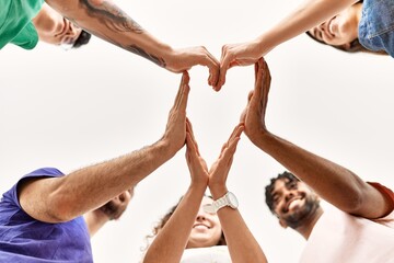 Group of young friends with hands together doing heart symbol.