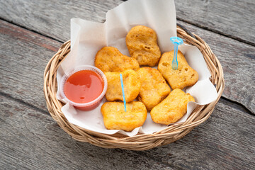 A plate of deep fired chicken nugget, served on old wooden surface table. Snack food close-up photo.