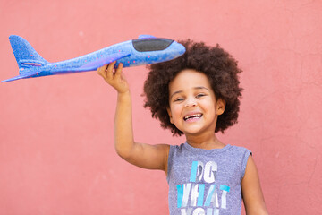 cute little black Afro American mixed race child playing with airplane	