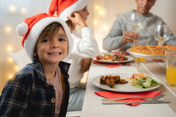 Happy family celebrating Christmas together with vegan dinner indoor at home - Focus on boy face