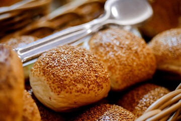 Closeup of fresh baked buns on tray. Buns with sesame seeds served for breakfast on buffet line.