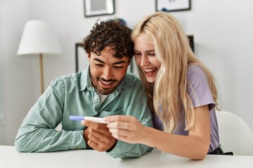 Young couple smiling happy looking pregnant test result at home.