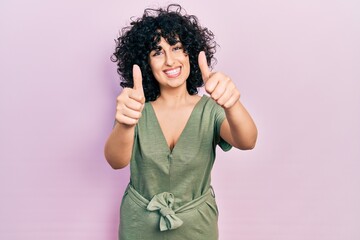 Young middle east woman wearing casual clothes approving doing positive gesture with hand, thumbs up smiling and happy for success. winner gesture.