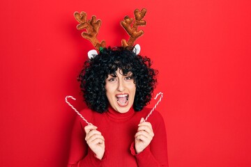 Young middle east woman wearing cute christmas reindeer horns celebrating crazy and amazed for...