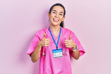 Young brunette woman wearing doctor uniform and stethoscope success sign doing positive gesture...