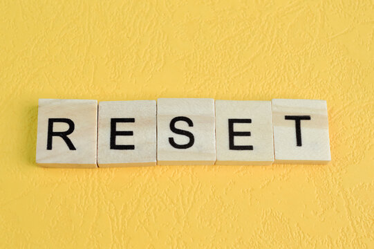 Wooden square letters with text RESET isolated on a yellow background