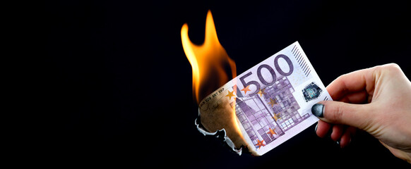 Five hundred Euros are burning with fire in hand isolated on black