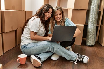 Young beautiul couple drinking coffee and using laptop at new home.