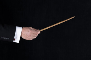hand with conductor baton on black background