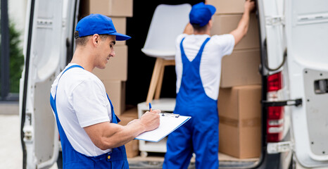 Two removal company workers are loading boxes into a minibus.