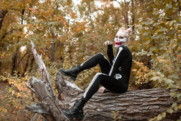 A girl with a scary make-up in a skeleton costume, a mask with rhinestones in a gloomy autumn...