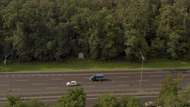 Boryspil highway near Kiev from a bird's eye view. Chausse passes through a dense green forest. The city of Kiev is visible ahead.