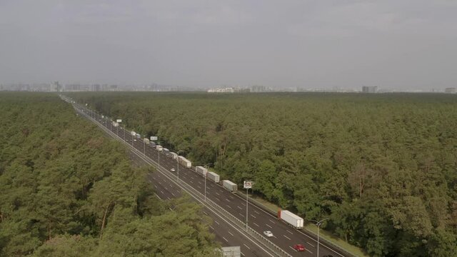 Boryspil highway near Kiev from a bird's eye view. Chausse passes through a dense green forest. The city of Kiev is visible ahead.