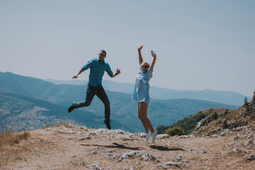 Freedom - Happy couple cheering and celebrating. Couple man and woman raising arms excited in celebration outdoors. Couple at sunset in mountain enjoying mountain top summit and success.