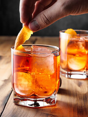 Two glasses with a Negroni cocktail on a wooden table. Vertical photo.