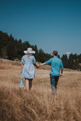 rear view of young couple walking hand in hand walking away. Man and woman walking in the mountain while holding hands.