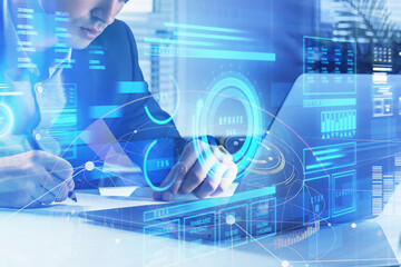 Businessman is taking notes in front of laptop with hologram