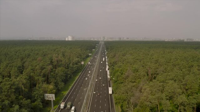 Boryspil highway near Kiev from a bird's eye view. Chausse passes through a dense green forest. The city of Kiev is visible ahead.