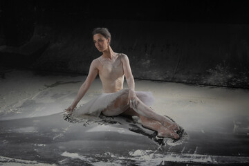 beautiful ballerina dancing in white flour near a black wall